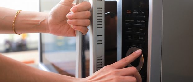 Woman's Hands Closing Microwave Oven Door And Preparing Food in microwave.